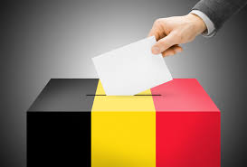 Une personne qui met son bulletin dans l'urne présentant les couleurs de la Belgique.